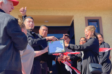 Board members from the Pinon Hills Chamber present Orlando with a membership plaque while  his mother, Maria, and father, Jesus, cut the ribbon.